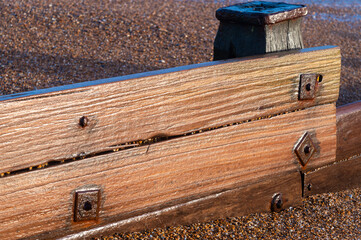 A beach groyne on the beach at Bexhill-on-Sea with waves and foam flowing over the shingle