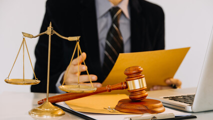 Business and lawyers discussing contract papers with brass scale on desk in office. Law, legal services, advice, justice and law concept.