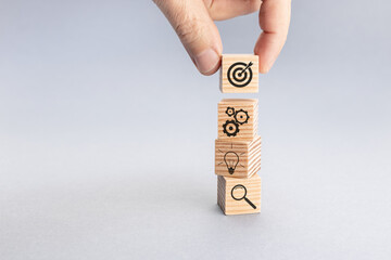 Business achievement goal and objective target concept. Hand putting wood block with target icon on...