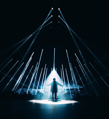 Homme silhouette avec jeux de lumières pour un concert de musique dans une salle en festival de nuit - obrazy, fototapety, plakaty