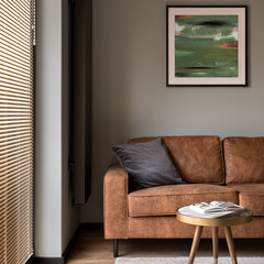 Brown couch under stylish painting