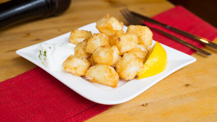 Chocos. Diced and battered squid served with lemon. Traditional Spanish tapa recipe.