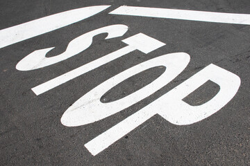 Large stop sign on road near crossing. Background traffic signals. Word stop on the ground. Roads, urban scene. 