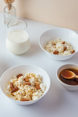 cottage cheese in a white bowl with nuts and honey on a light ba