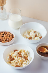 cottage cheese in a white bowl with nuts and honey on a light ba
