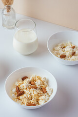 cottage cheese in a white bowl with nuts and honey on a light ba