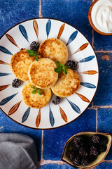 cottage cheese pancakes on a plate, blackberries, sour cream. br