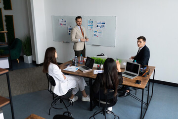 a group of entrepreneurs of different nationalities at a table in the office solve a business problem together