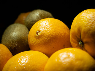 Owoce pomarańczy i kiwi na czarnym tle. Selektywny fokus na błyszczącą skórkę owoców.