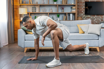 Obraz premium Sport activities at home. Young man doing exercises and lunges i