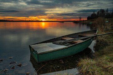 Łódka na tle wschodzącego słońca nad jeziorem Pogoria IV