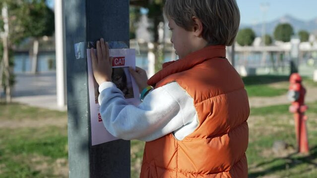 Schoolboy putting up missing pet banners.