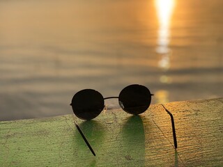 Fototapeta na wymiar black round glasses and sunset background on the beach