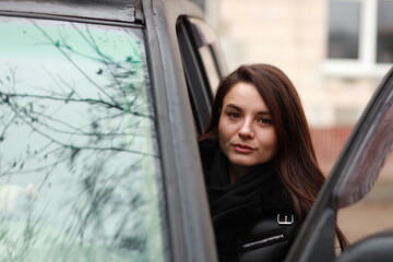 Fototapeta na wymiar Beautiful young brunette woman at big black car