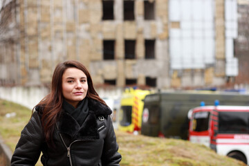 Ukrainian young woman near ambulance at damaged building