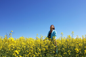 A woman in a field with yellow flowers on a blue sky background