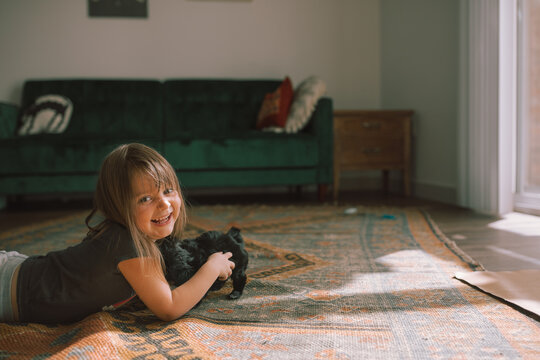 Child playing with black puppy maltese in boho styled room