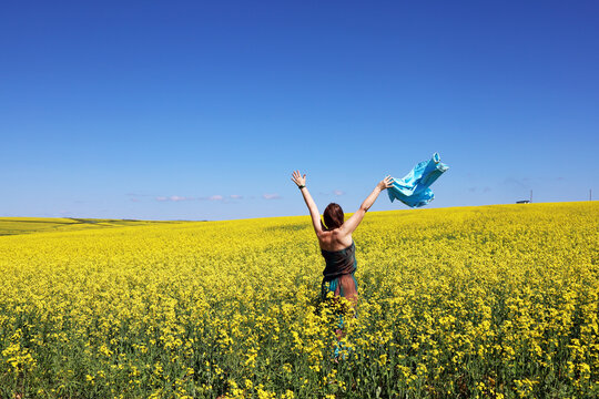 A woman in a field with yellow flowers on a blue sky background