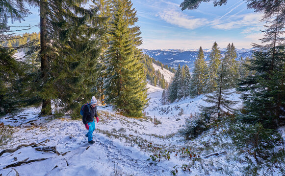 nice senior woman hiking on sunny day in the snowy landscape of the Allgaeu Alps above Oberstaufen, Bavaria, Germany