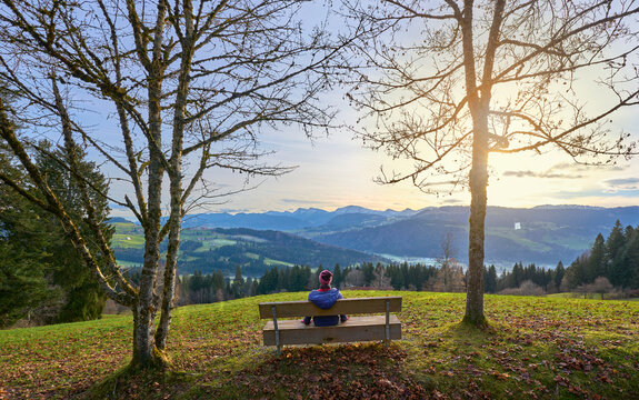 Woman resting at a viewpoint at sunrise in the Allgaeu mountains, near Oberstaufen, Bavaria, Germany