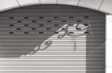 Light and shadow on surface of the old roller shutter door in arch door frame of vintage house in...