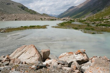 Scenery of Tian Shan Mountains during trekking in Altyn Arashan Valley to glacier. Little lake at foot of glacier. Karakol National Park. Kyrgyzstan, Central Asia