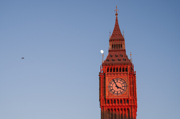 Fototapeta na wymiar Travel to England, landmark photo. Big Ben tower clock building after renovation during a beautiful sunset with moon rising in background against clear sky.