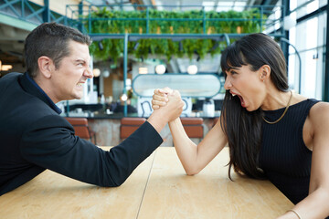 man and woman arm wrestling competition on the table