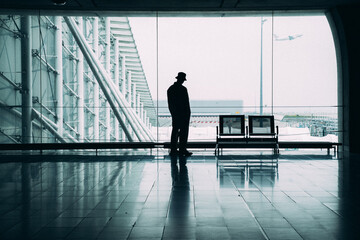 silhouette homme d'affaire debout devant fenêtre d'un aéroport avec un avion qui décolle