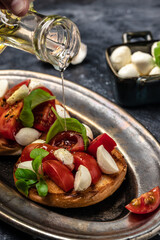 Caprese toasts with mozzarella, cherry tomatoes and fresh garden basil. Traditional italian appetizer or snack, antipasto. vertical image. top view. place for text