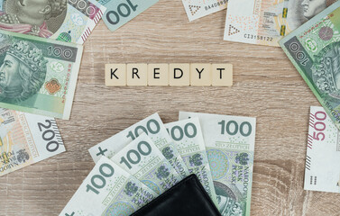 Word kredyt in Polish language, means loan or mortgage. Buying a house or apartment in Poland. Flat lay composition with złoty money, PLN zloty banknotes.