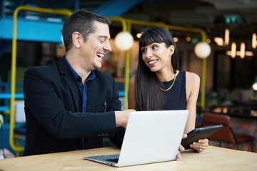 businesswoman and businessman or couple talking and working together with laptop computer in a cafe