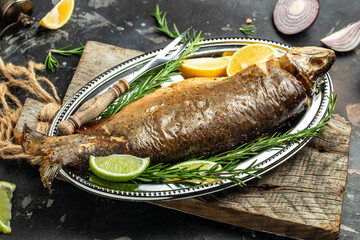 baked fish with lemon herbs and spices on a dark background. Clean eating, dieting, vegan food concept. top view