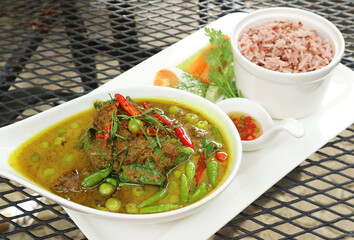 Hot and Spicy Thai Green Curry with Beef and a Bowl of Cooked Thai Red Cargo Rice in the Backdrop