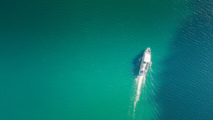 Top view of a white boat sailing in the blue lake