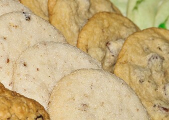 Homemade assorted cookies arranged and displayed in rows diagonally. Sugar, raisin and oatmeal flavors displayed, closeup with selective focus.
