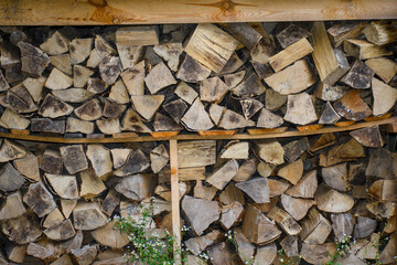 Duże kawałki poukładanego drewna opałowego leżące na stercie, zapas na zimę 