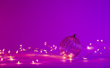 Christmas neon background with garland and Christmas ball, copy space.