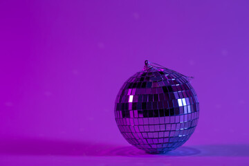 Disco ball on a blurred purple background, the concept of dancing, disco, music and parties, copy space.