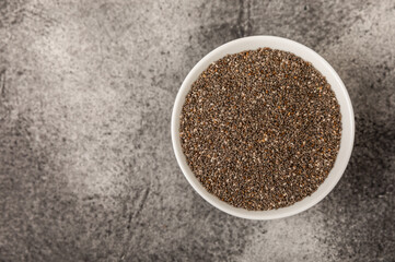 Chia seeds in a bowl on a black texture background.Superfood and axiontidant. Diet. Close-up. Place for text. Copy space.