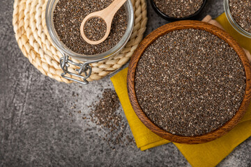 Chia seeds in a spoon and bowl on a black texture background.Superfood and axiontidant. Diet. Close-up. Place for text. Copy space.