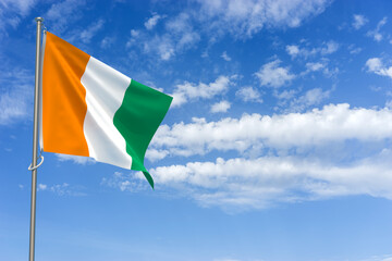 Republic of Cote d'Ivoire Flag Over Blue Sky Background. 3D Illustration