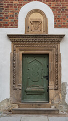 Elegant old doors adorned with intricate details in a decorated façade of a historical significant building, well-maintained, showing the craftsmanship of the ornate carvings and moldings.