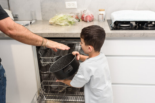 Father And Son Unloading Dishwasher Together. Chores Concept.