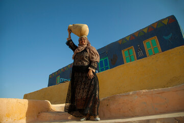 a Nubian girl holding a nile water pot in village in aswan
