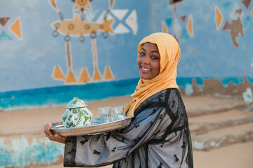 A Nubian girl carrying a teapot - obrazy, fototapety, plakaty