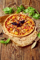 Delicious pizza served in country style with green salad ornament on wooden table with free space for text.