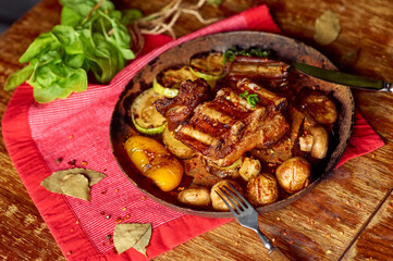 Roasted pork ribs with grilled vegetables in a pan. Meat grilled close up
