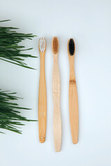 Wooden, bamboo toothbrushes on a white background with green grass. Eco friendly products. Flat lay
