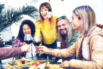 Group of happy multiracial friends drinking and cheers red wine glasses at bar restaurant-Trendy people having fun  at dinner party in a winery pub-Food,Beverage Lifestyle and friendship concept